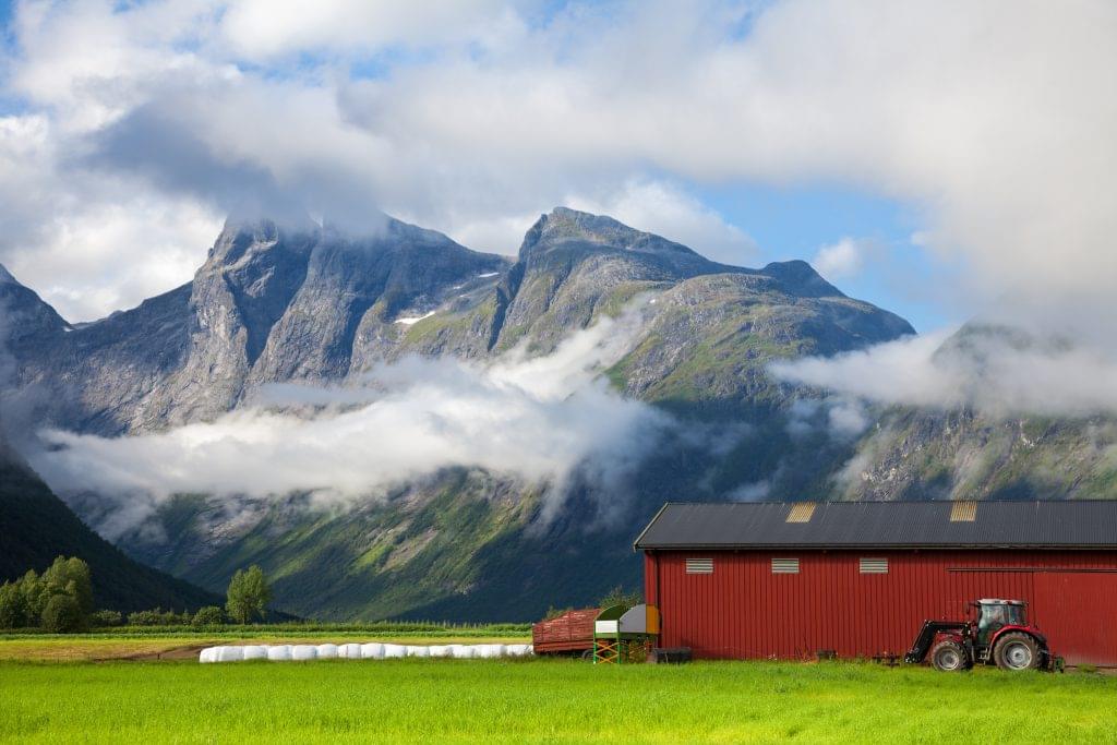 En gård i Norge med et fjell i bakgrunnen